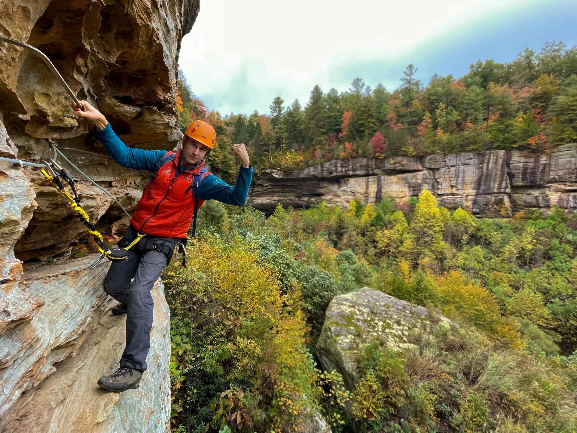 Climber on the Torrent Falls via ferrata with fall foliage in the background